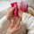 Hands applying Tropic’s Passion Flower & Pink Pepper enveloping hand cream from a pink tube, dispensing the nourishing cream onto the palm.